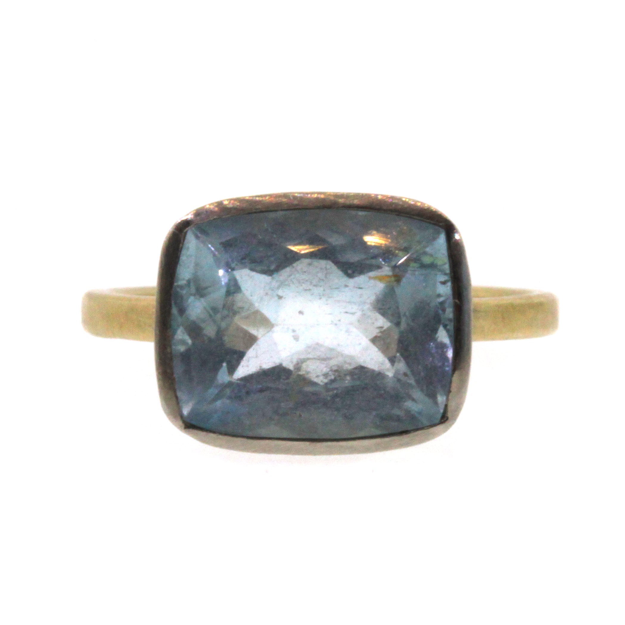 This Cushion Aquamarine Ring was handcrafted by Rebecca Lankford. It features a brilliant, blue aquamarine bezel set in white gold and soldered into a textured yellow gold band. 