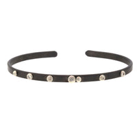 This Scattered Diamond Cuff Bracelet was handcrafted by Rebecca Lankford in Houston Heights. It features 7 diamond bezel set in sterling silver and scattered onto a thin rhodium plated cuff.