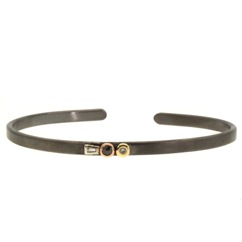 Mixed Metal Diamond Cuff was handcrafted by Rebecca Lankford at her studio in Houston, Texas. It features a baguette diamond set in white gold, a brown round diamond set in rose gold, and a round white diamond set in yellow gold all hand picked and soldered onto a thin black rhodium plated cuff. 
